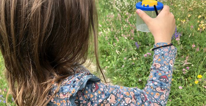 Kind entdeckt mit Becherlupe die Natur auf dem Weltacker